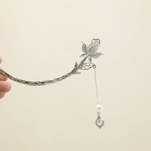 Detail view of silver rose hair pin with white cat-eye stone, pearl, and tassel charm