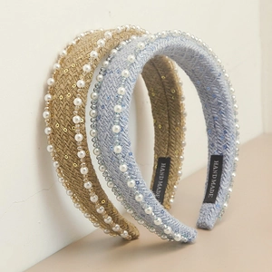 Detail of handmade knitted headbands with white pearls and sequins on a textured surface