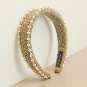 Detailed macro view of woven straw headband with white pearls and handmade label