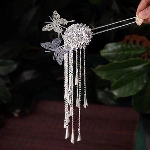 Detail of silver butterfly hair pin with long tassels and intricate hollow metalwork