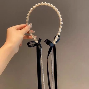Detailed view of pearl headband with black velvet bows and dangling rhinestone tassels