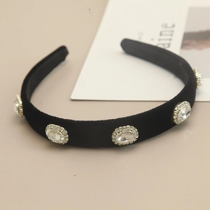 Detail showing five oval crystals with fine rhinestones on a wide black velvet headband