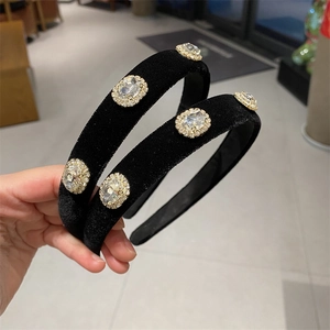 Detail of two black velvet headbands featuring large oval rhinestones with crystal borders