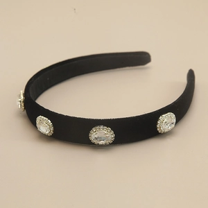 Elegant black velvet headband with vintage oval rhinestones on a minimalist background