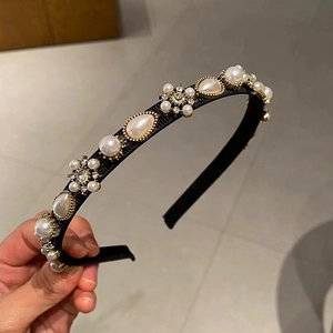 Detail of drop pearls and rhinestones on a black fabric headband with gold settings