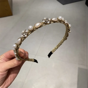 Close-up of golden pearl headband with delicate rhinestones and woven metal details