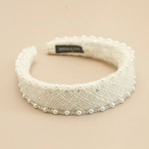 Detailed close-up of cream knit headband with pearls and handmade woven texture