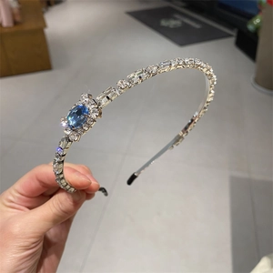 Detailed close-up of crystal headband featuring a blue oval gemstone and silver metal base