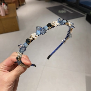 Detail eines blauen Kristall-Haarreifs mit weißen Perlen und feinem Strassbesatz