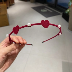Detail of red velvet headband with alternating white pearls and heart shaped accents