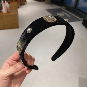 Detail of a wide black velvet headband with vintage rhinestones in a retail shop setting