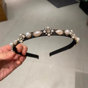 Detailed macro view of the black fabric headband with white pearls and rhinestones