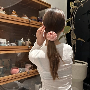 Elegante elastico per capelli con rosa in raso rosa indossato su una coda di cavallo