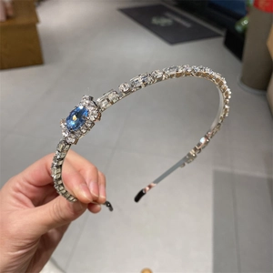 Elegant silver metal headband with white rhinestones and a large blue oval gemstone