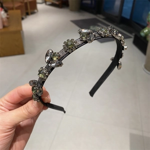 Macro detail of hand-set grey and champagne gemstones on a leaf-style headband