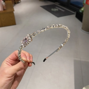 Elegant crystal headband with rectangular rhinestones on a slim metal frame held by hand