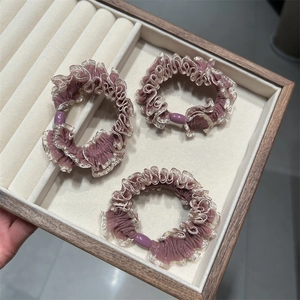 Gros plan de trois chouchous en dentelle violette avec bordure dorée dans un plateau