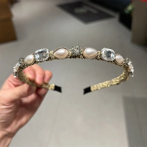 Dettaglio cerchietto vintage dorato con cristalli rettangolari e perle stile palazzo