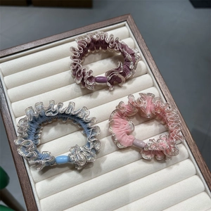 Gros plan détaillé de trois chouchous en velours avec dentelle argentée et perles rondes