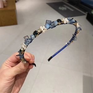 Detailaufnahme von blauen Kristallen und weißen Perlenblüten auf einem Seidenstirnband