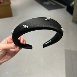 Macro shot of padded satin headband with sparkling rhinestones and white pearls
