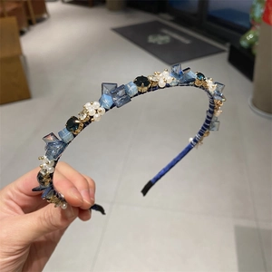 Detailaufnahme von Kristall- und Perlenverzierungen auf einem blauen Samtstirnband