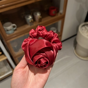Macro di un elastico per capelli a rosa in seta bordeaux con elegante trama satinata e pieghe