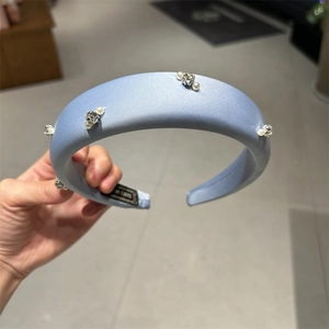Detail of wide light blue satin headband with white pearls and sparkling rhinestones