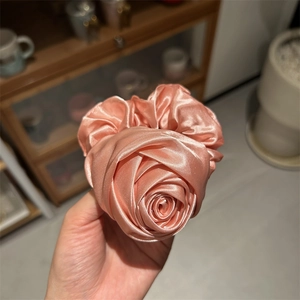 Dettaglio di un elastico in raso rosa con petali di fiori 3D stratificati