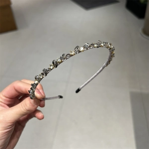 Close-up of thin headband decorated with gray and gold crystal stones and protective tips