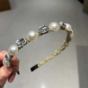 Dettaglio del cerchietto vintage dorato con perle e cristalli quadrati in tessuto intrecciato