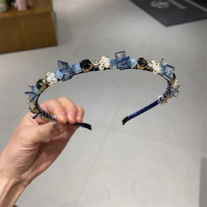 Detail eines blauen Samtstirnbands mit Kristallen und weißen Perlenclustern