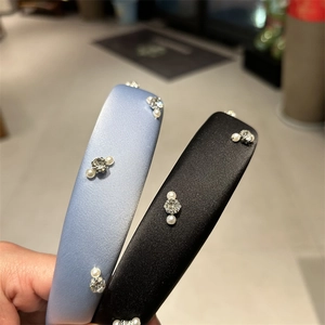 Detail of satin headbands with rhinestones and pearls on light blue and black fabrics