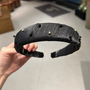 Vue détaillée du serre-tête en tissu noir orné de cristaux élégants et de perles dorées