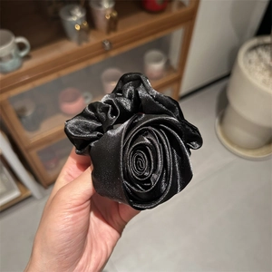 Dettaglio di un elastico per capelli a rosa in raso nero con texture in seta lucida