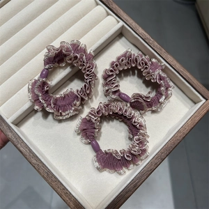 Détails de chouchous violets avec bordure dorée présentés sur un plateau en velours