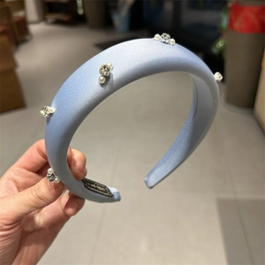 Macro detail of a light blue satin sponge headband with elegant pearls and rhinestones
