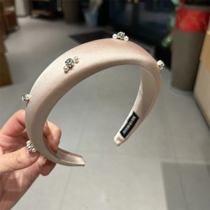 Detail showing the handmade label on the satin padded headband with pearls and rhinestones