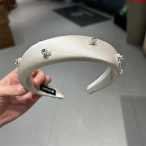 Detail of handmade cream satin headband with pearls and rhinestones showing hand made label