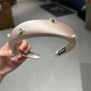 Detail of champagne satin headband with white pearls and sparkling crystal embellishments