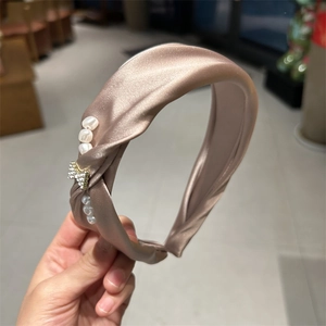 Detail of champagne gold satin headband with elegant pearls and rhinestone bow