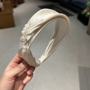 Detail of champagne knotted headband with pearls and a sparkling metal bow decoration