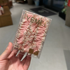 Détail d'un chouchou en dentelle plissée rose avec couture dorée dans son coffret
