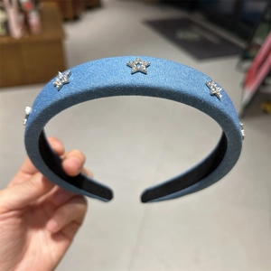 Détail d'un serre-tête en jean bleu orné de décorations en forme d'étoiles scintillantes