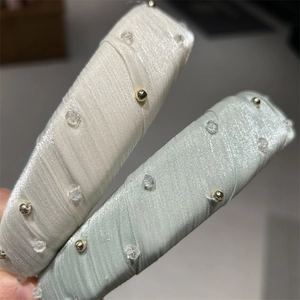 Gros plan de serre-têtes en tissu rembourré avec perles dorées et cristaux étincelants