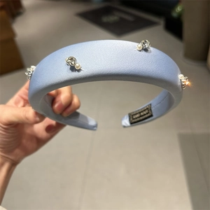 Close-up of light blue satin headband with pearl and crystal beads and handmade label
