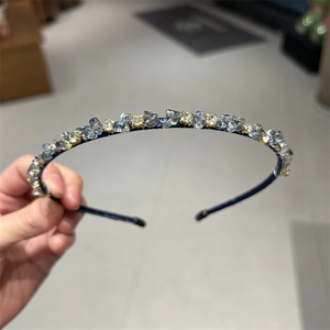 Detail of blue crushed stones and rhinestones on thin gold headband for women