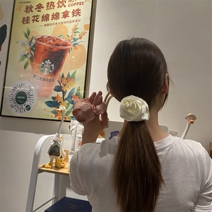 Dettaglio di elastici per capelli a forma di rosa in raso color crema e rosa