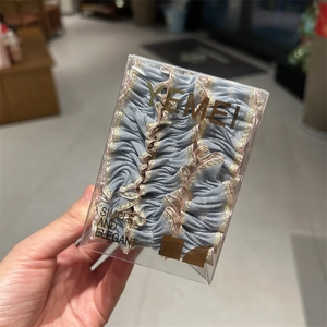 Détail d'un chouchou bleu clair à volants avec bords dorés dans un emballage clair