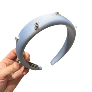 Handmade light blue sponge headband with pearls and rhinestones on a white background